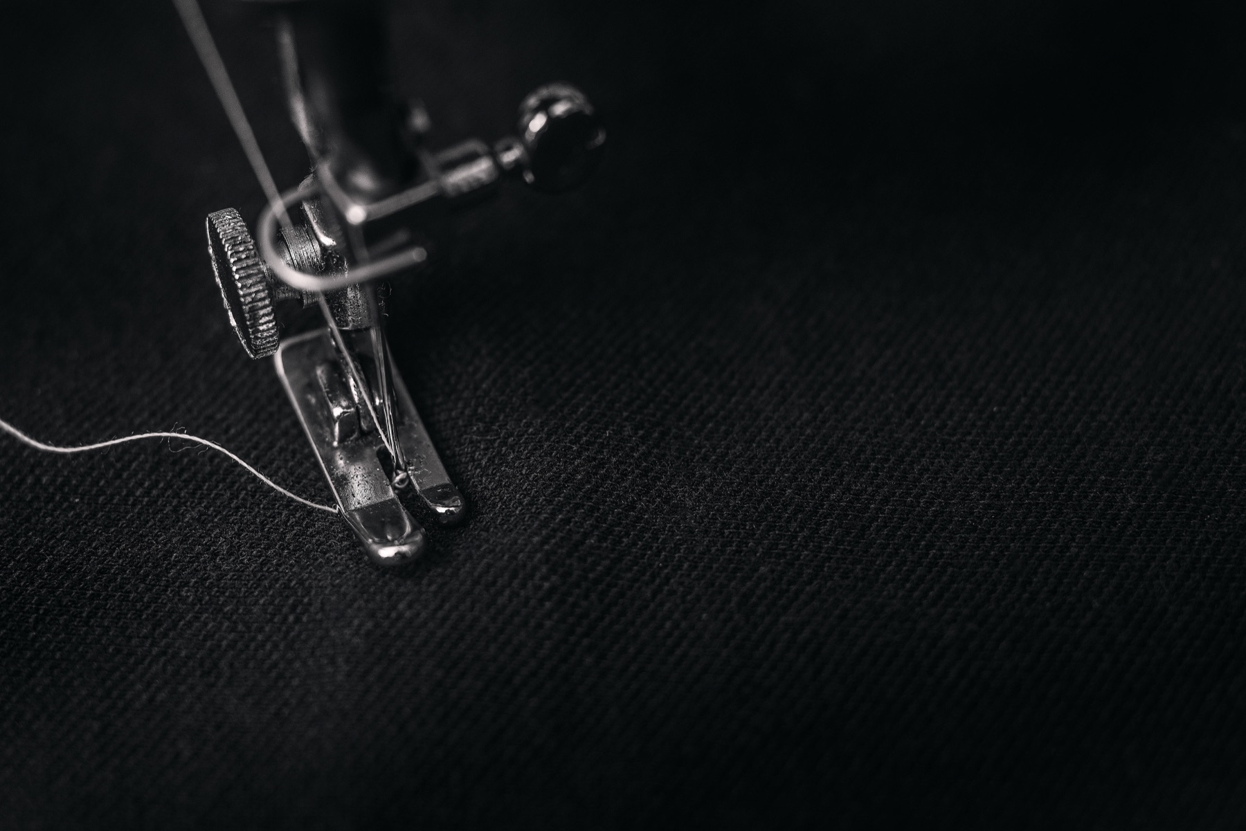 Sewing corporate uniforms in the Bongist Koncepts workshop in Uyo, Nigeria — a needle and presser foot stitching dark fabric